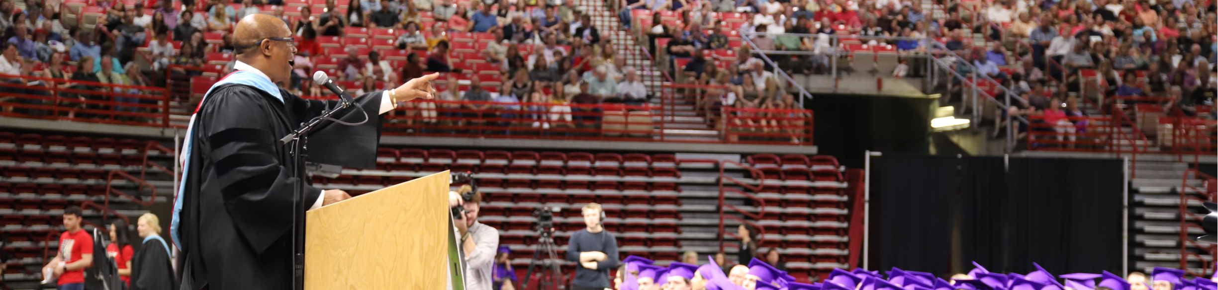 About Us - Picture of Superintendent speaking at graduation