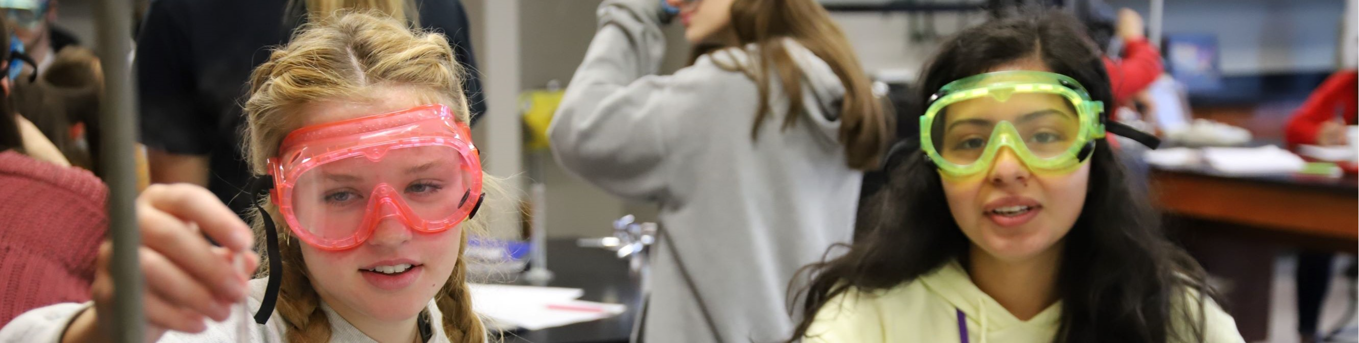 Two students conducting a Chemistry experiment with goggles on.