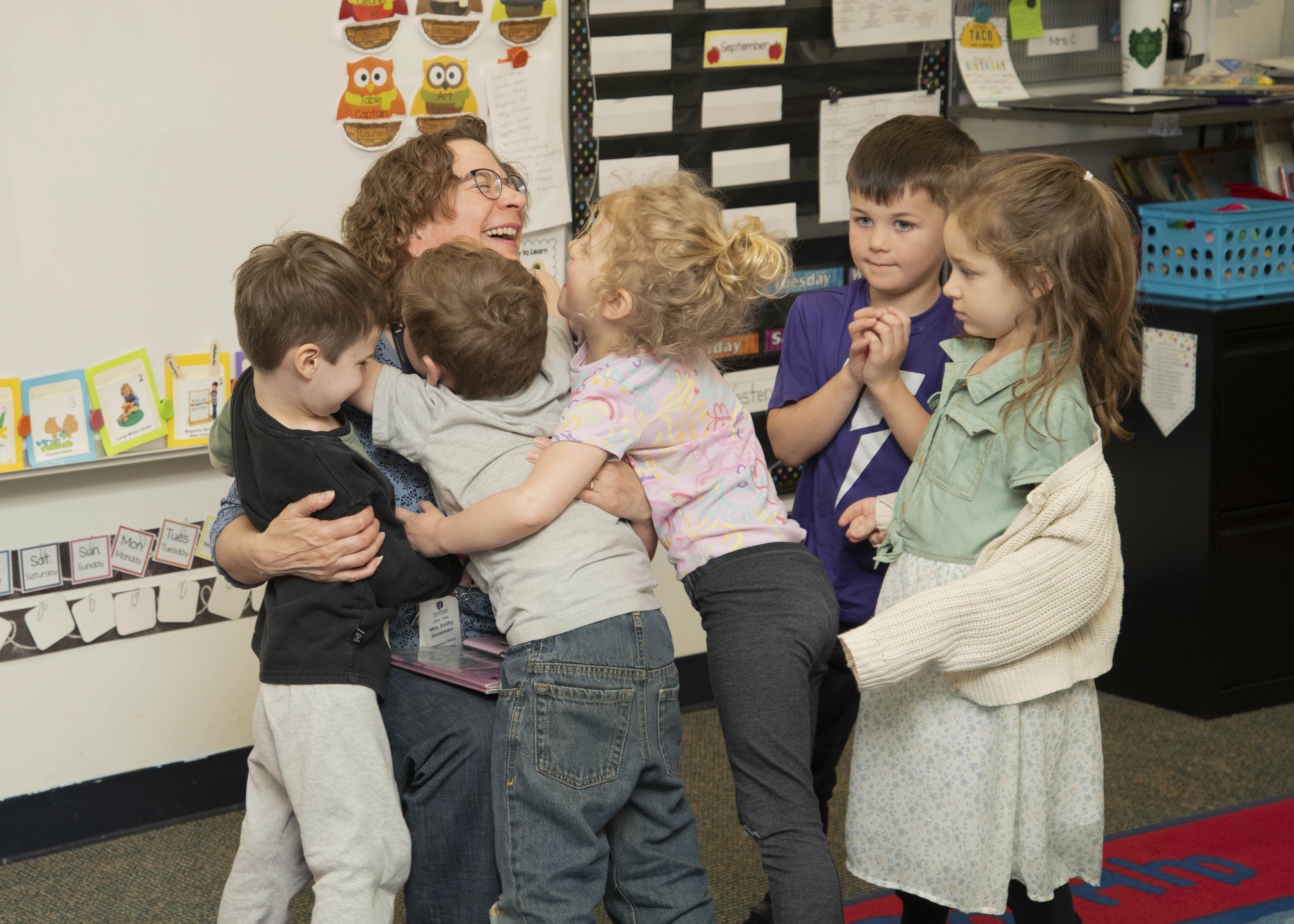 students hugging teacher