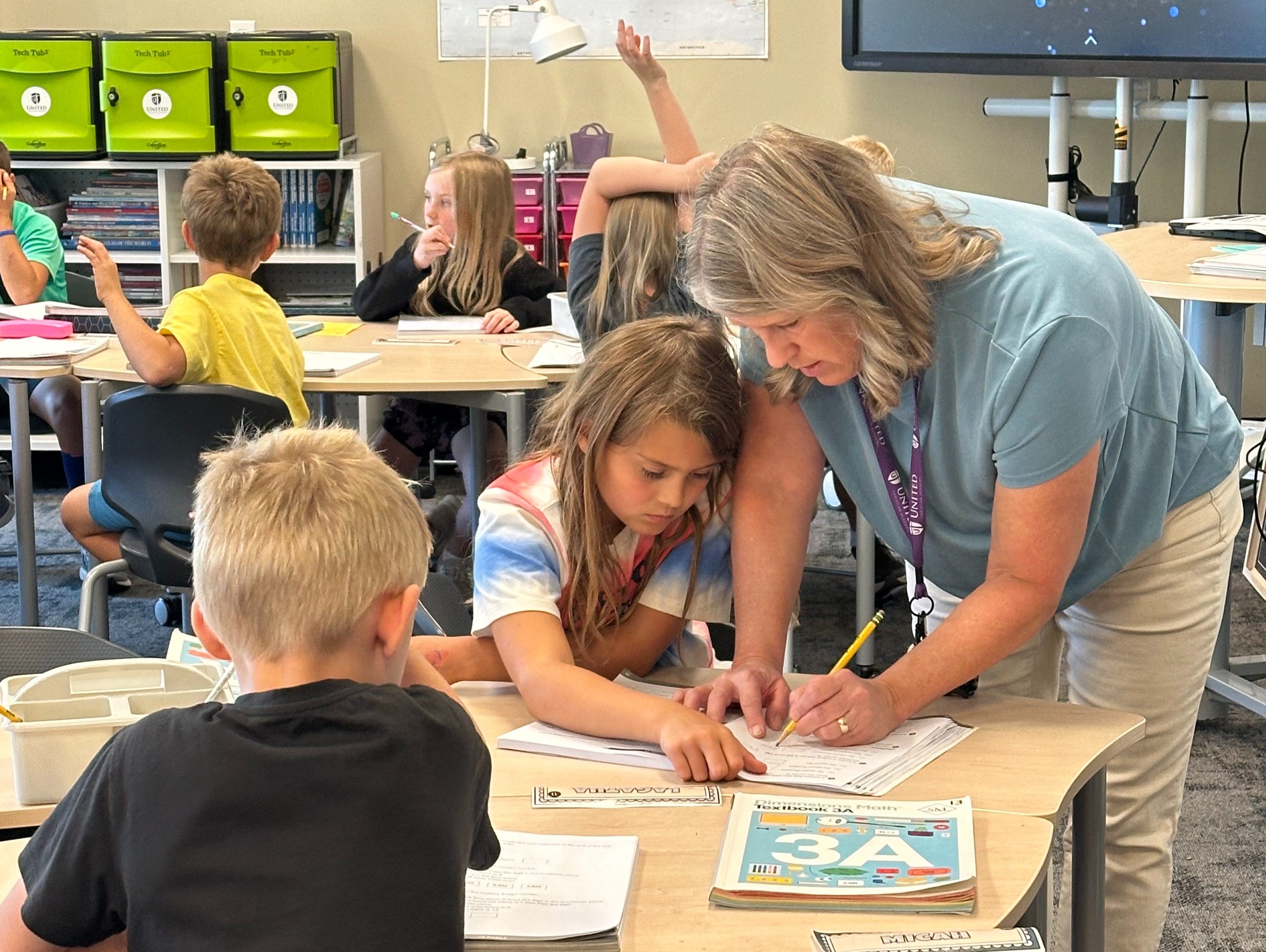 teacher helping a student at her desk