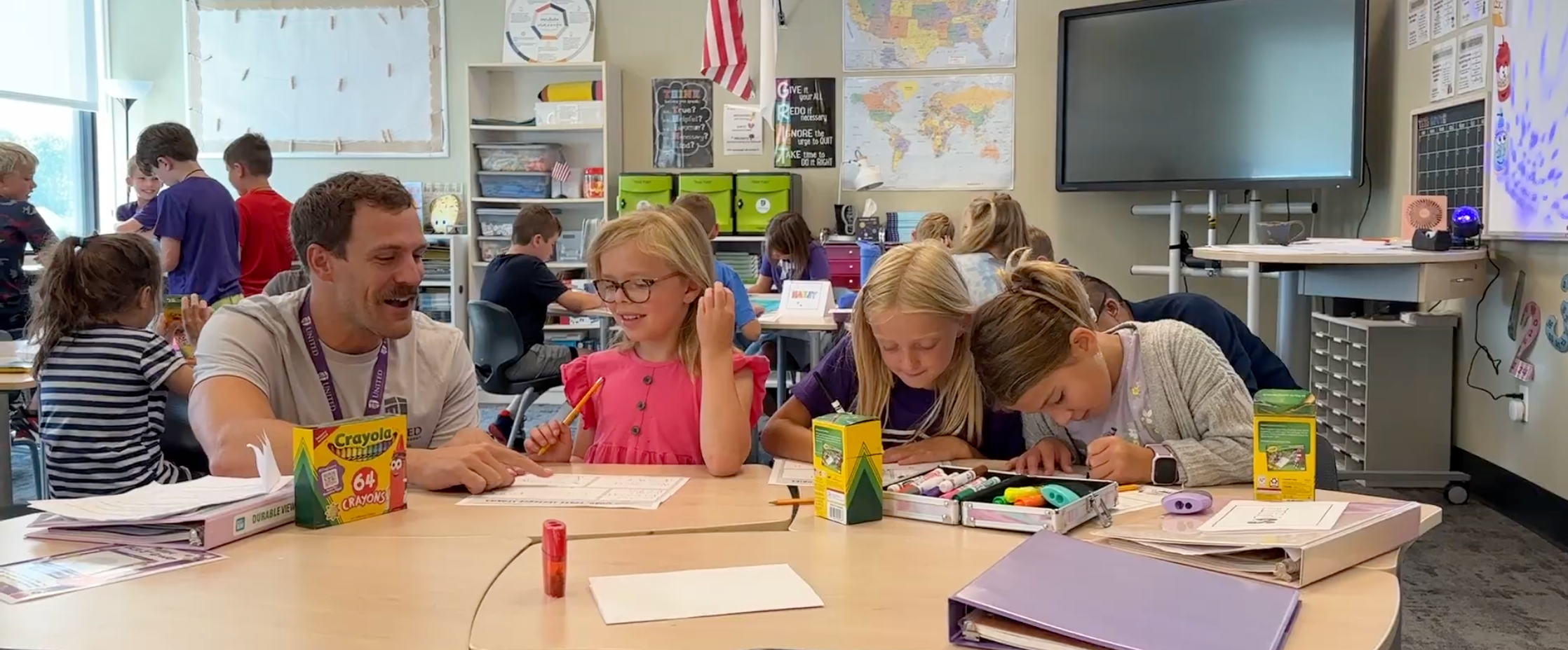 teacher helping students at their desk