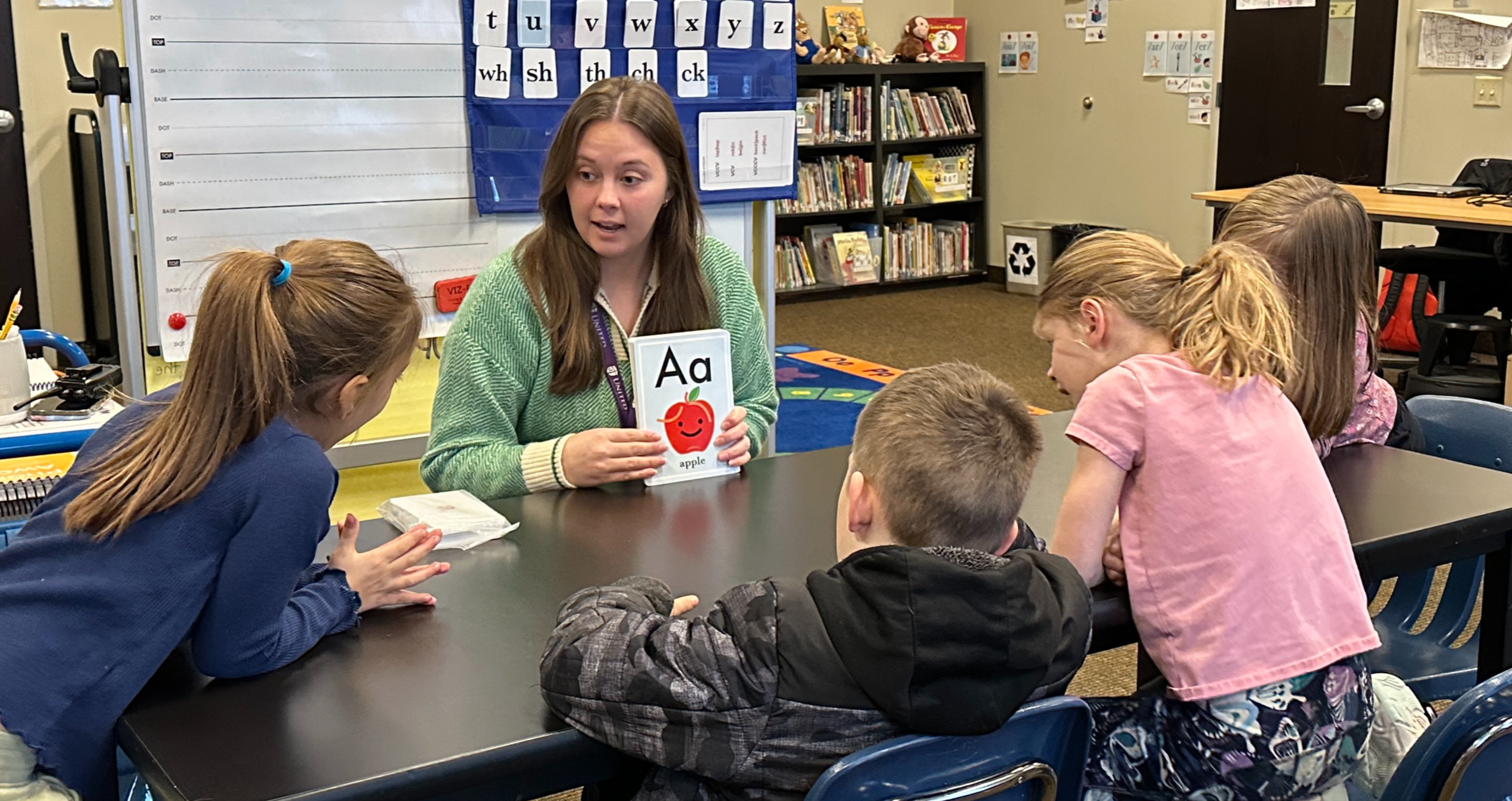 teacher working with a small group of students on letter sounds