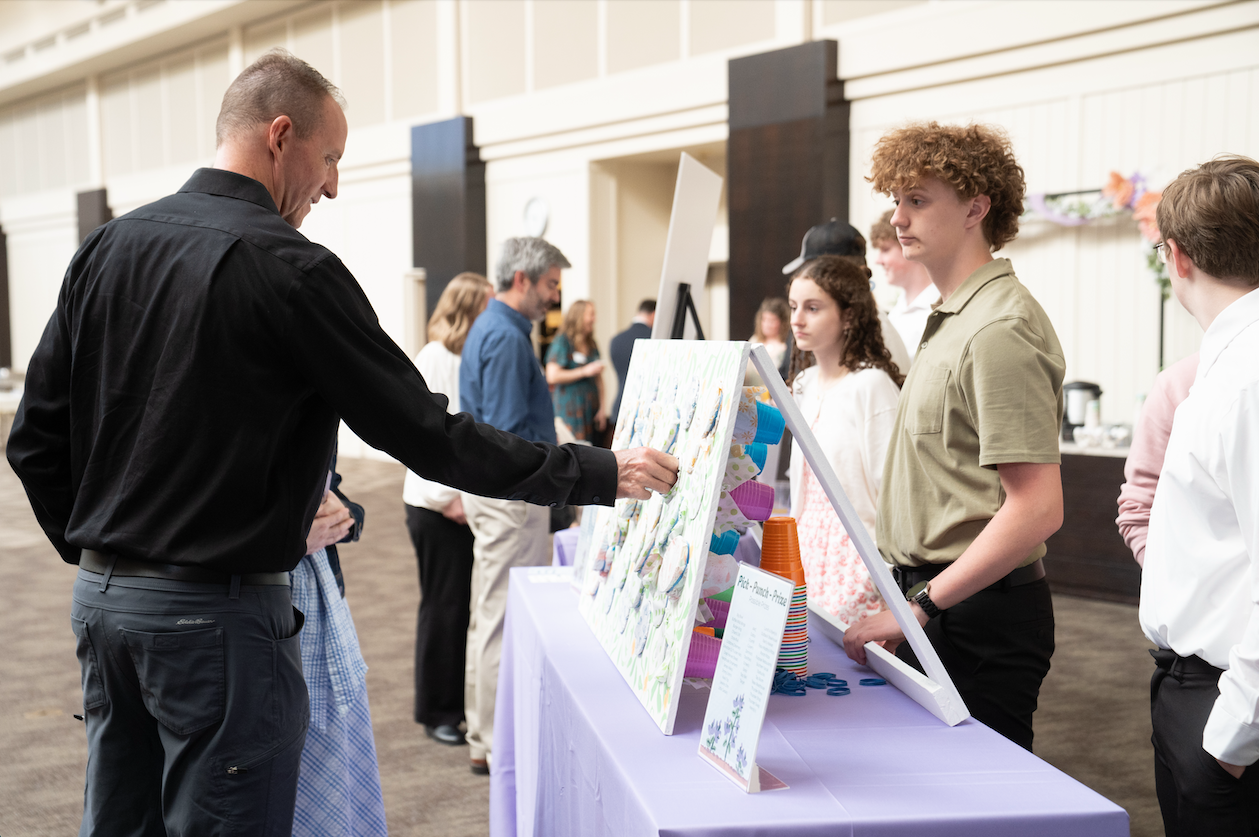 students working at a raffle table and guests buying tickets