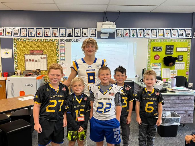 High School football player posing with Elementary football players