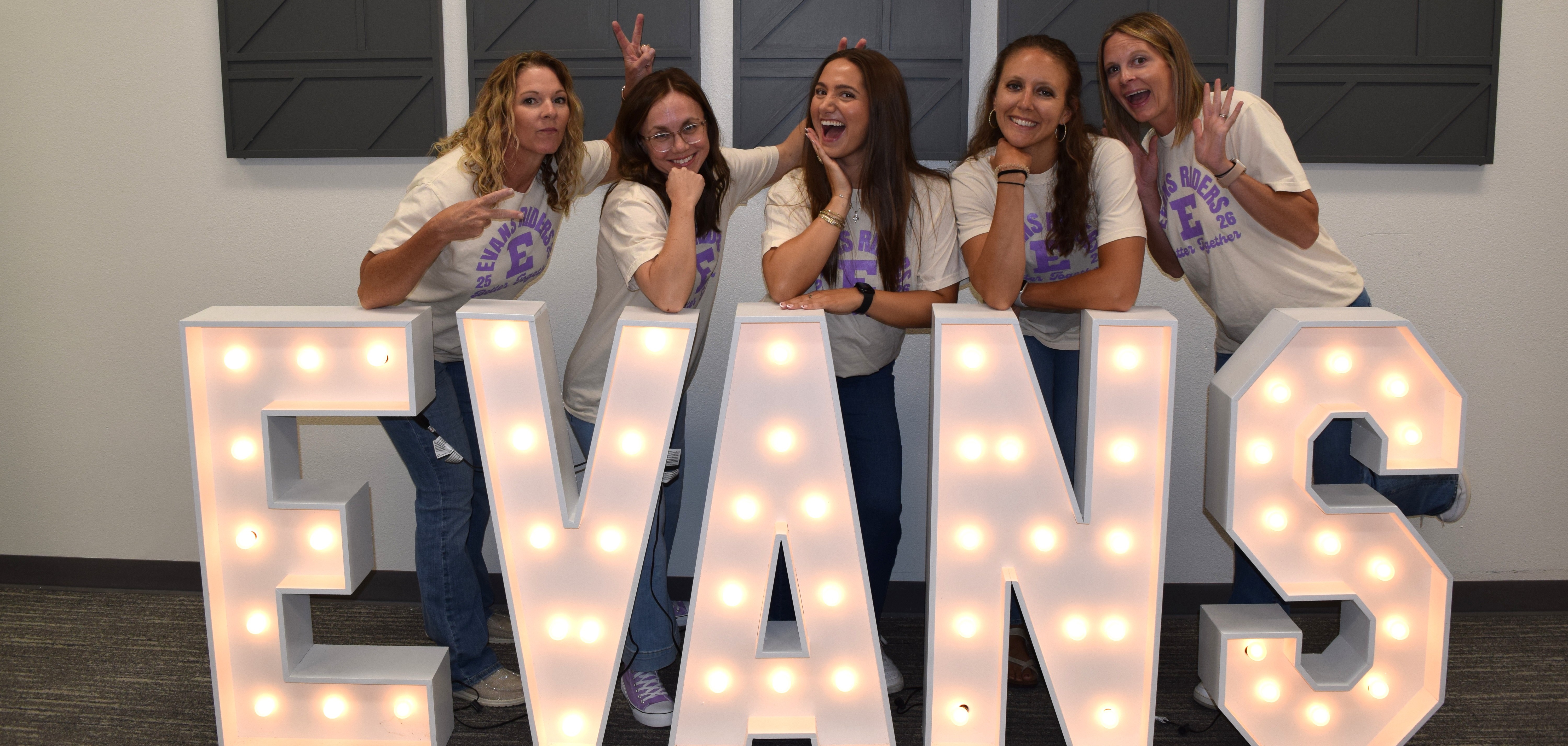 teacher standing behind Evans sign