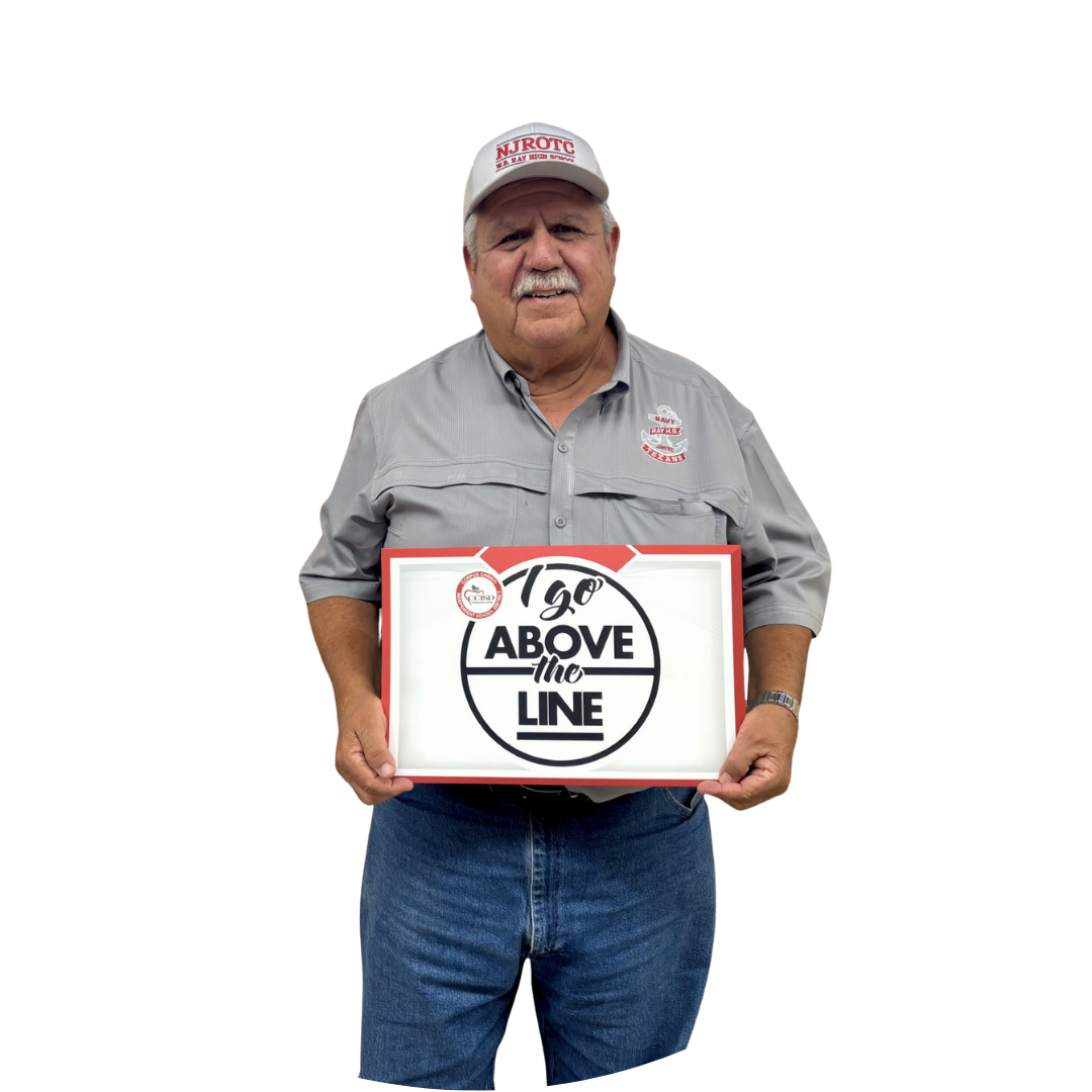 Man wearing gray shirt and white cap holding sign that reads "We Go Above the Line."