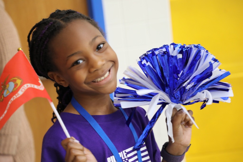 Student waves a pom pom and a US Marines flag at B. M. Williams Primary School during a parade for its military families to celebrate April as the Month of the Military Child