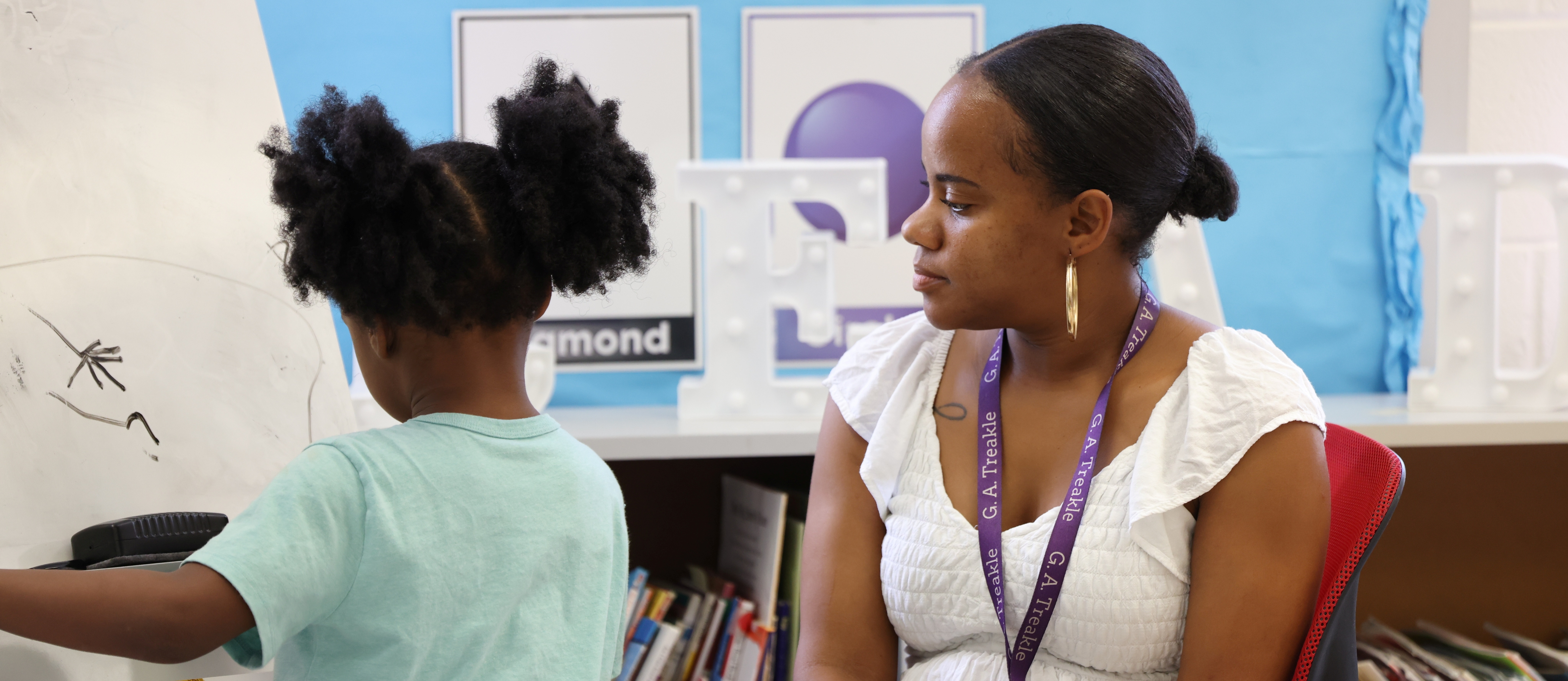 A G.A. Treakle Elementary teacher works with a young student as she particpates in an activity