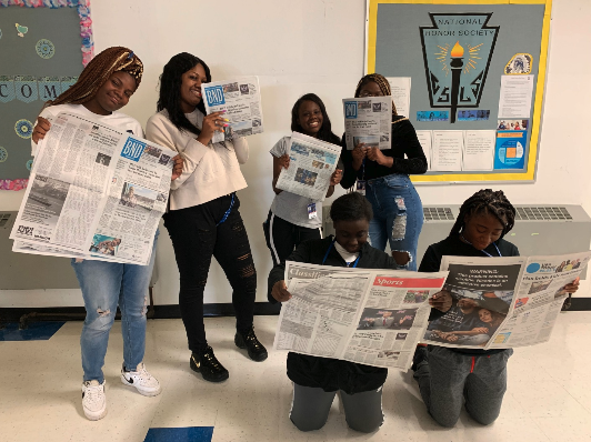 student reporters reading a newspaper 