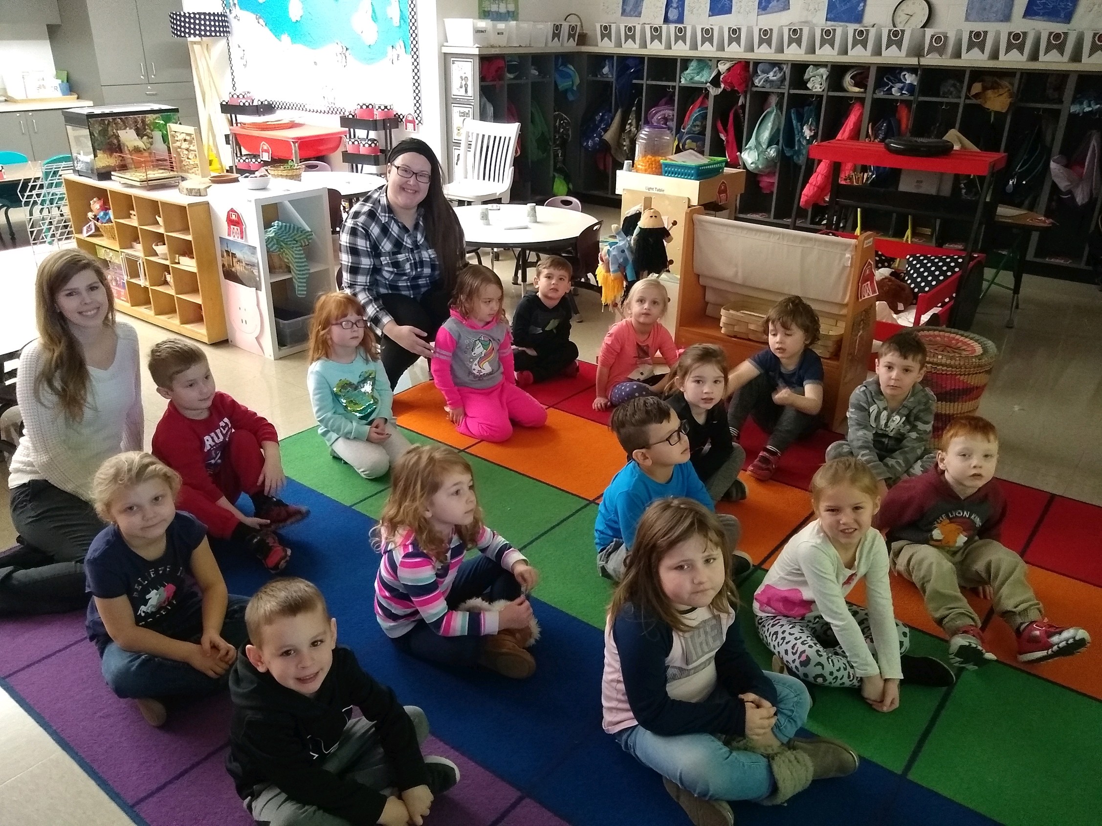 A group of 15 PRE-K kids inside a classroom along with their 2 teachers.