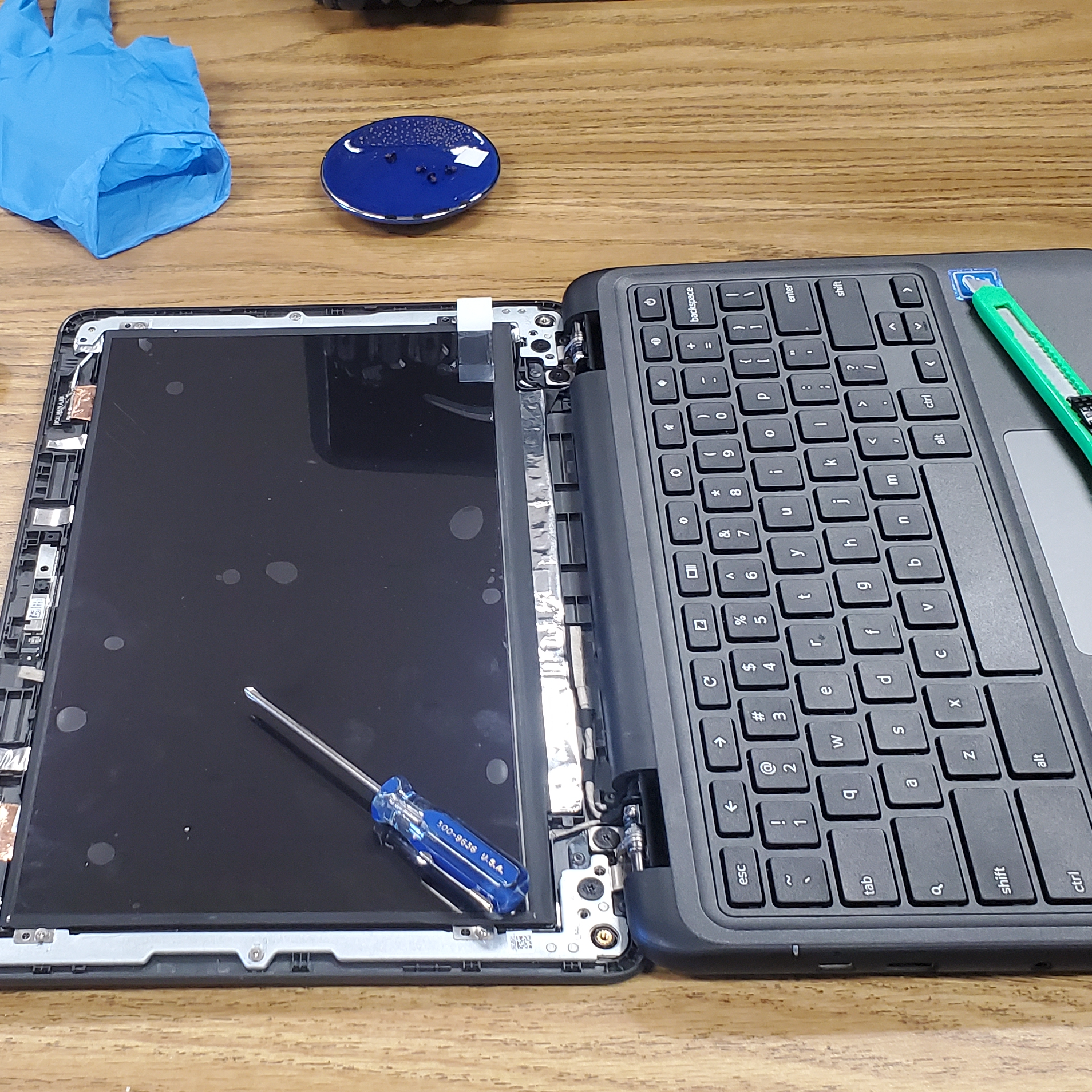 Chromebook or laptop disassembled to repair. The screen is exposed with the front cover removed.