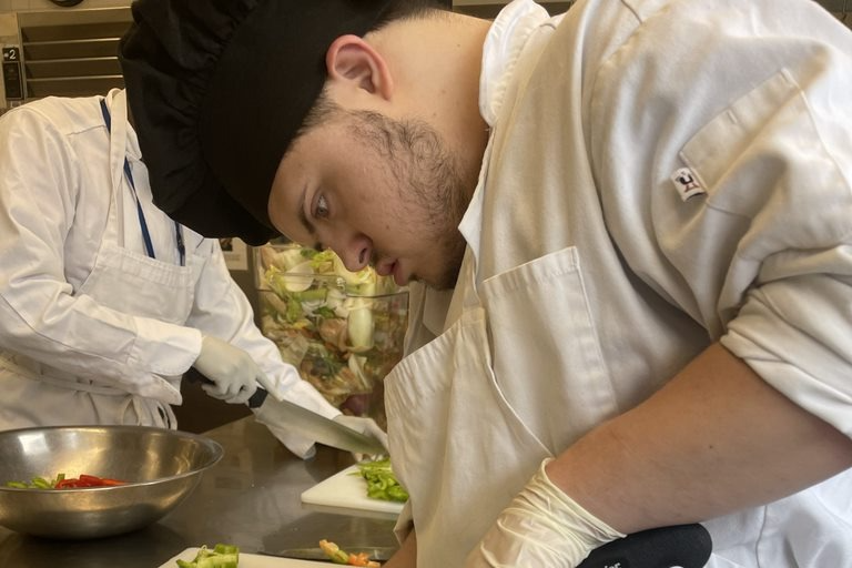 Student chef cutting peppers