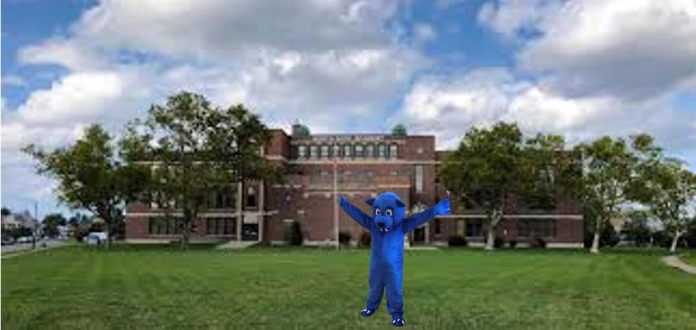 Blue pepper the panther mascot standing outside of the school building