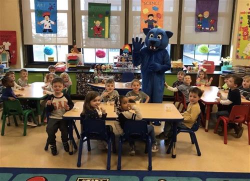 Pepper the blue panther standing in a classroom with students seated at their desks