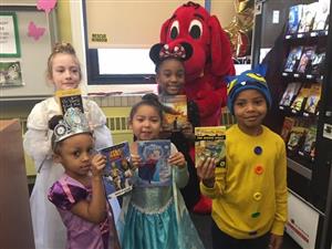 students holding books and standing next to clifford