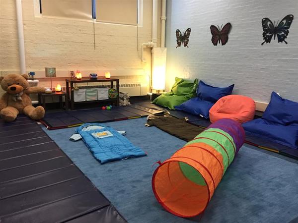 room with 3 butterflies on wall, teddy bear, bean bags, and sleeping bag