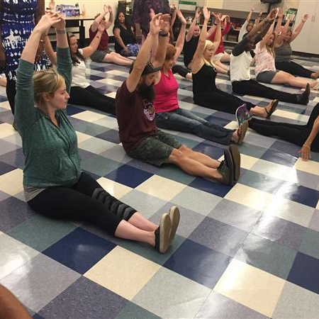 people stretching in a class with their arms up