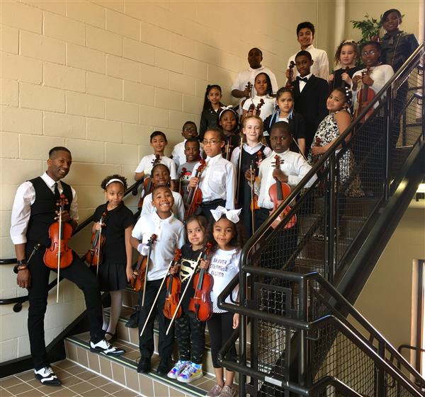 students smiling on steps with violin