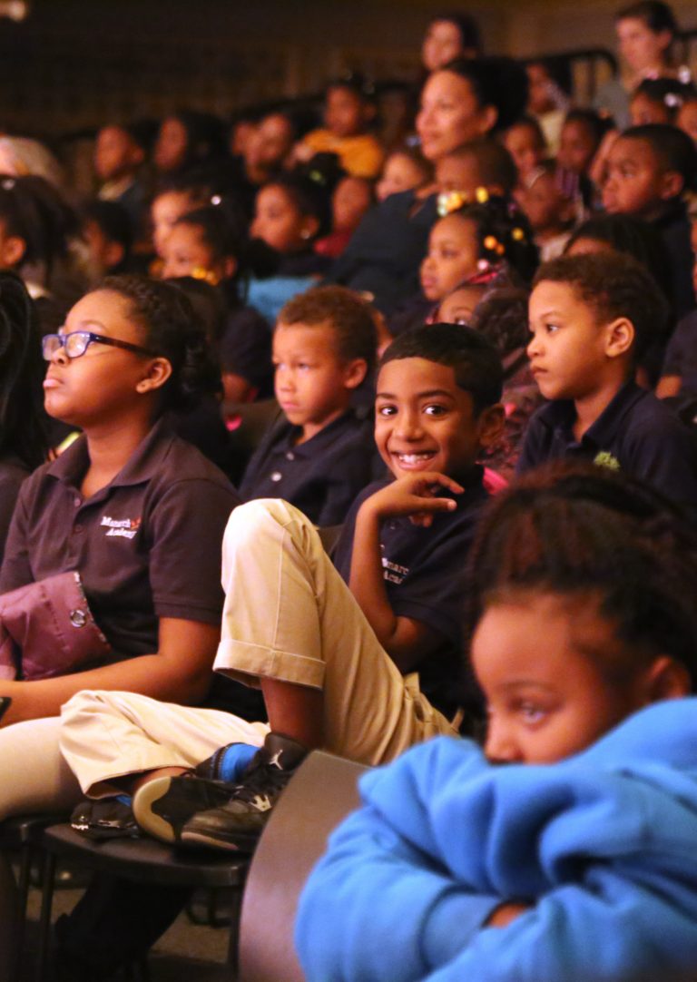 Kid sitting in the Auditorium smiling to the camera