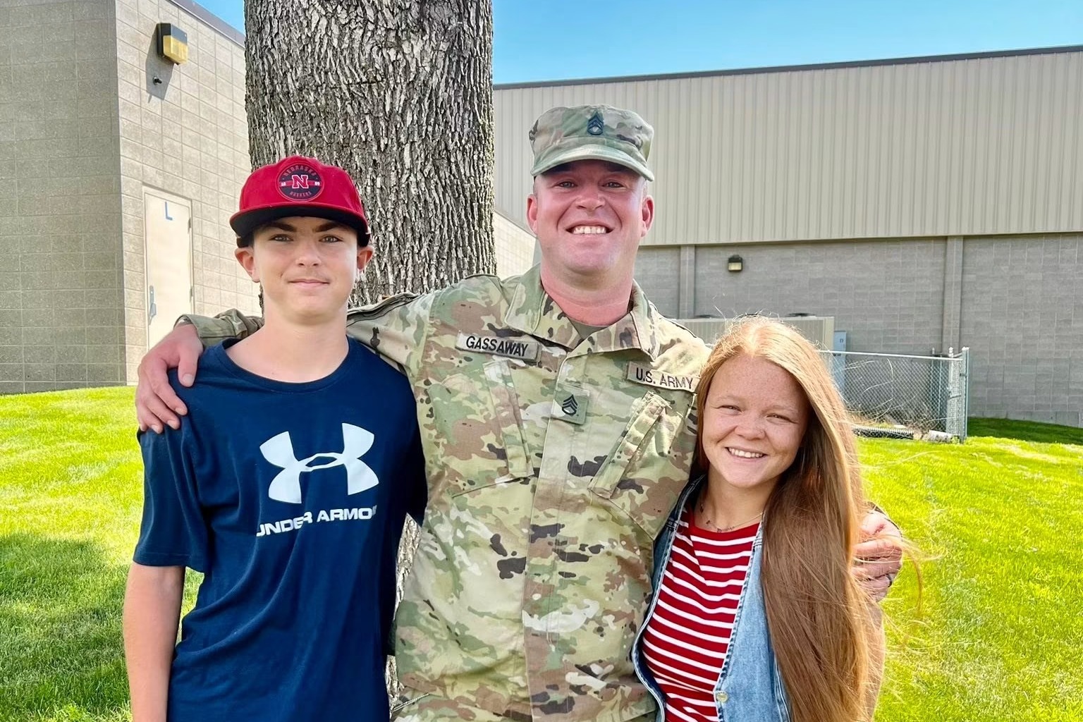 Two children pose with their father who is dressed in miliary garb