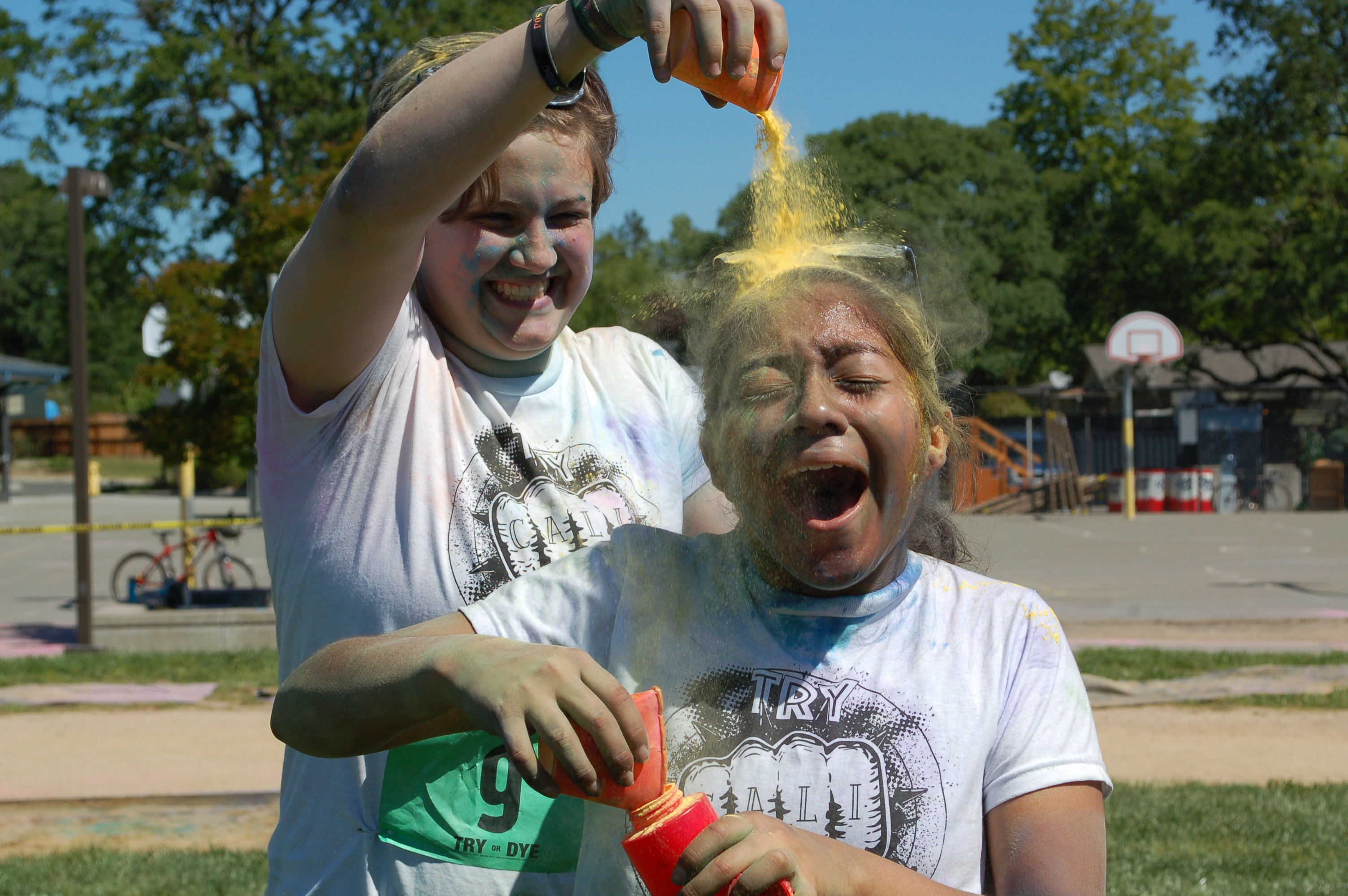 A photo of a student and a staff member playing with color powders.