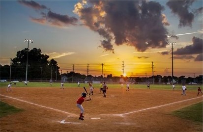 Kids playing baseball at sunset in the Arlington Sports Complex park