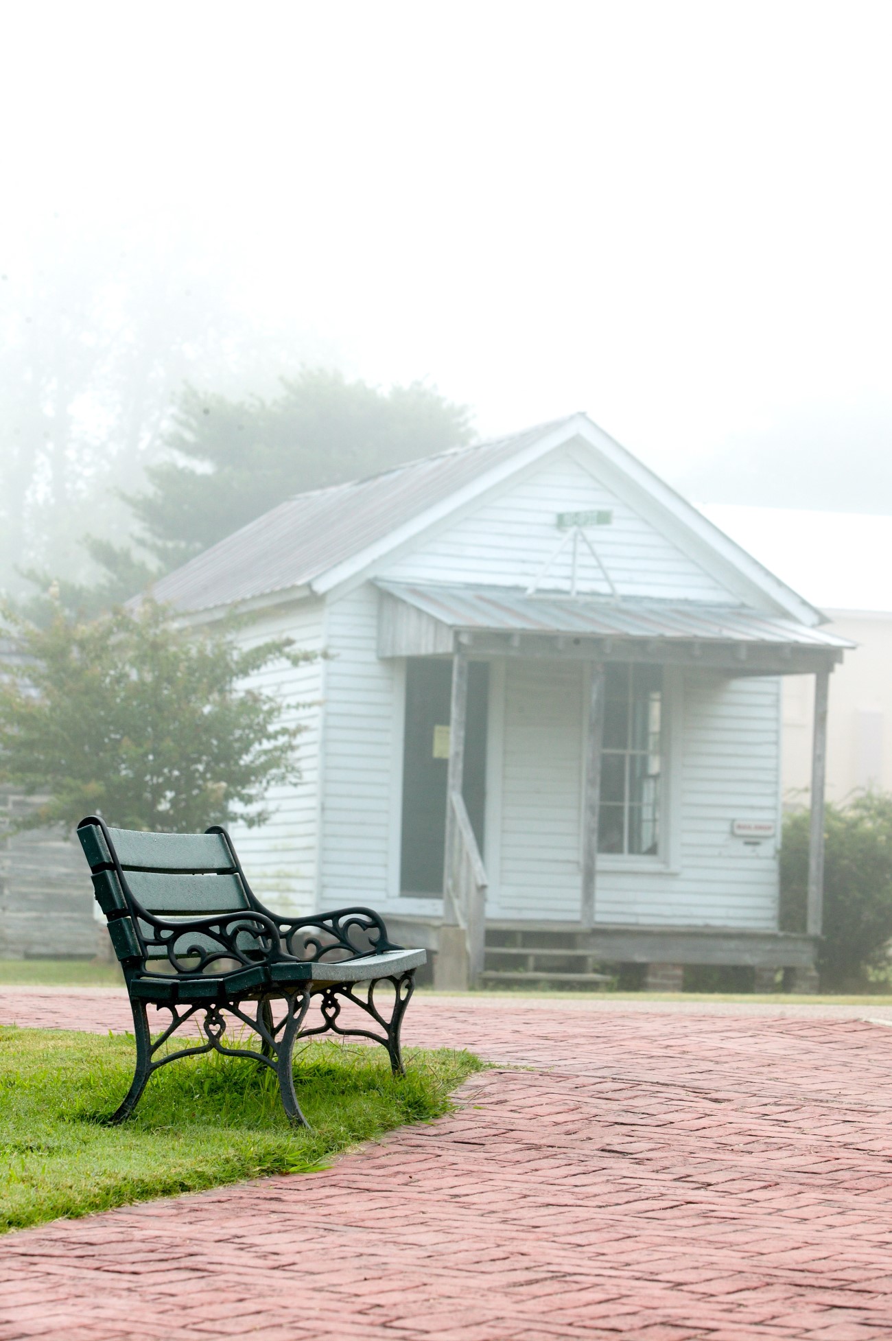 Historic Post Office in fog with metal bench on brick walkway