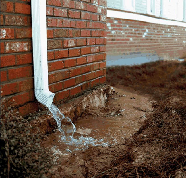 water leaving a white downspout on a brick building