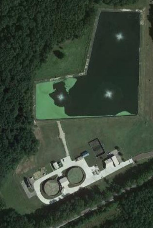 Aerial view of Arlington Wastewater Treatment Plant, showing buildings and ponds surrounded by trees
