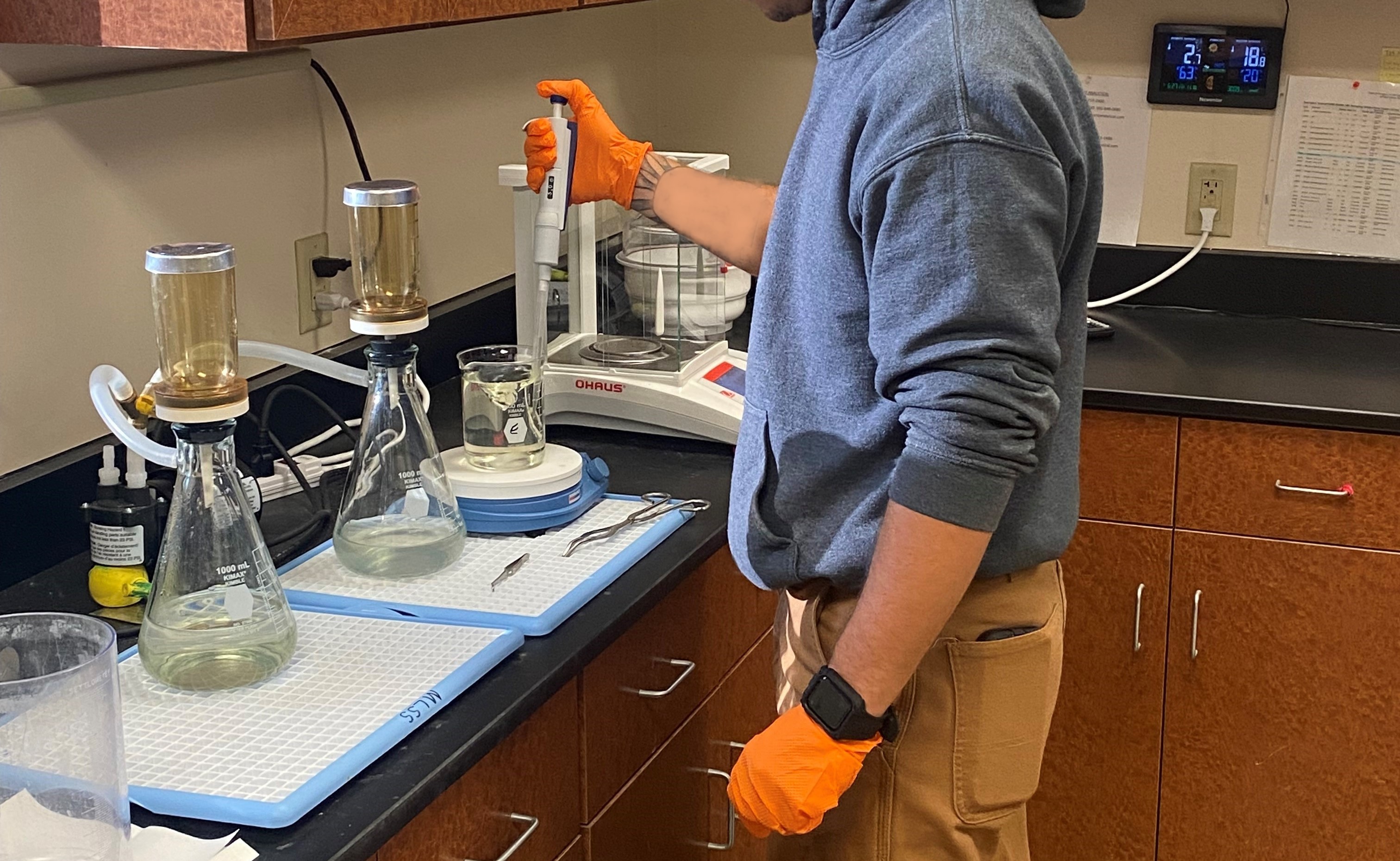 Person standing at a counter with beakers and other lab equipment