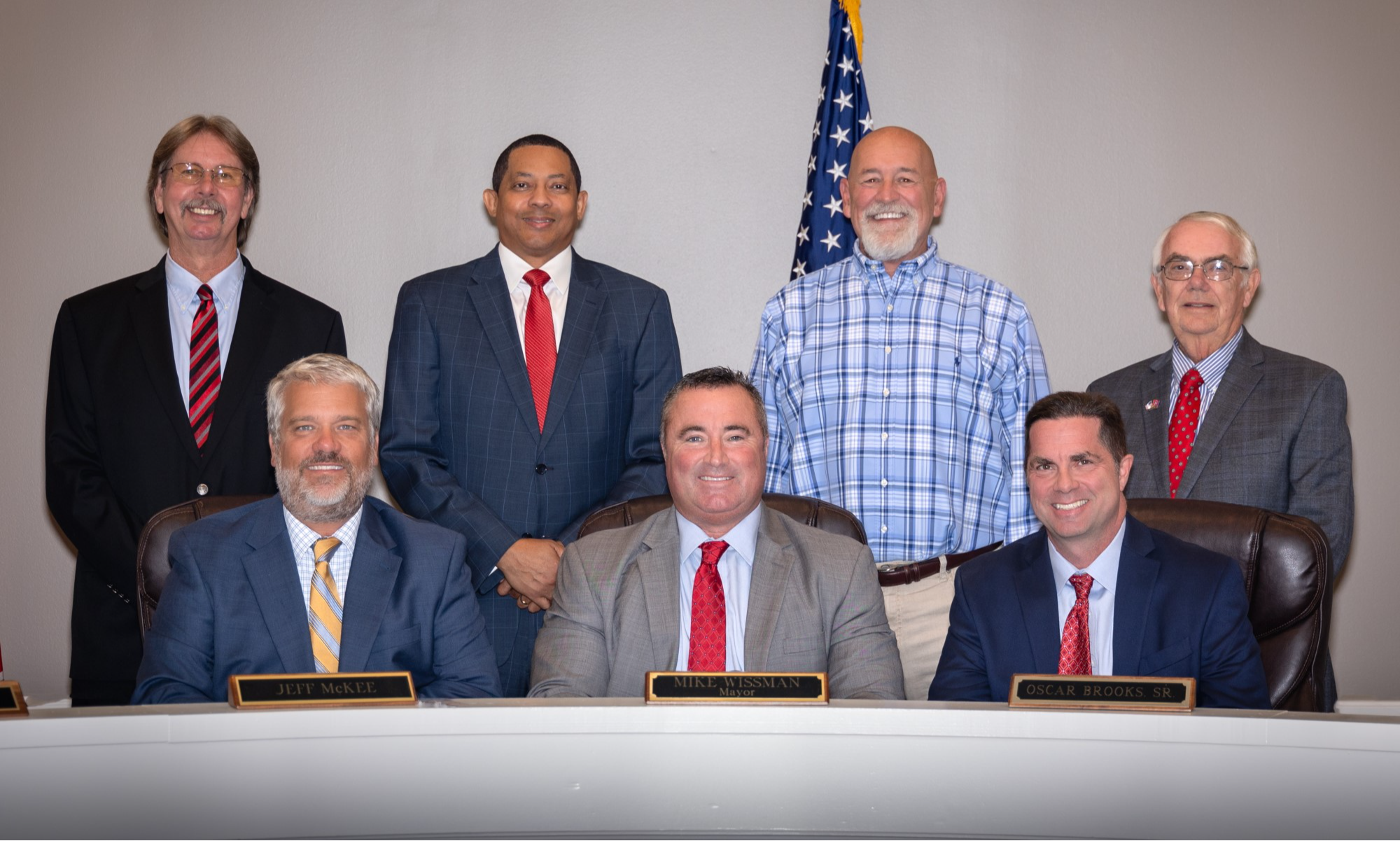 Seven Elected officials posed in a group shot with US flag behind them