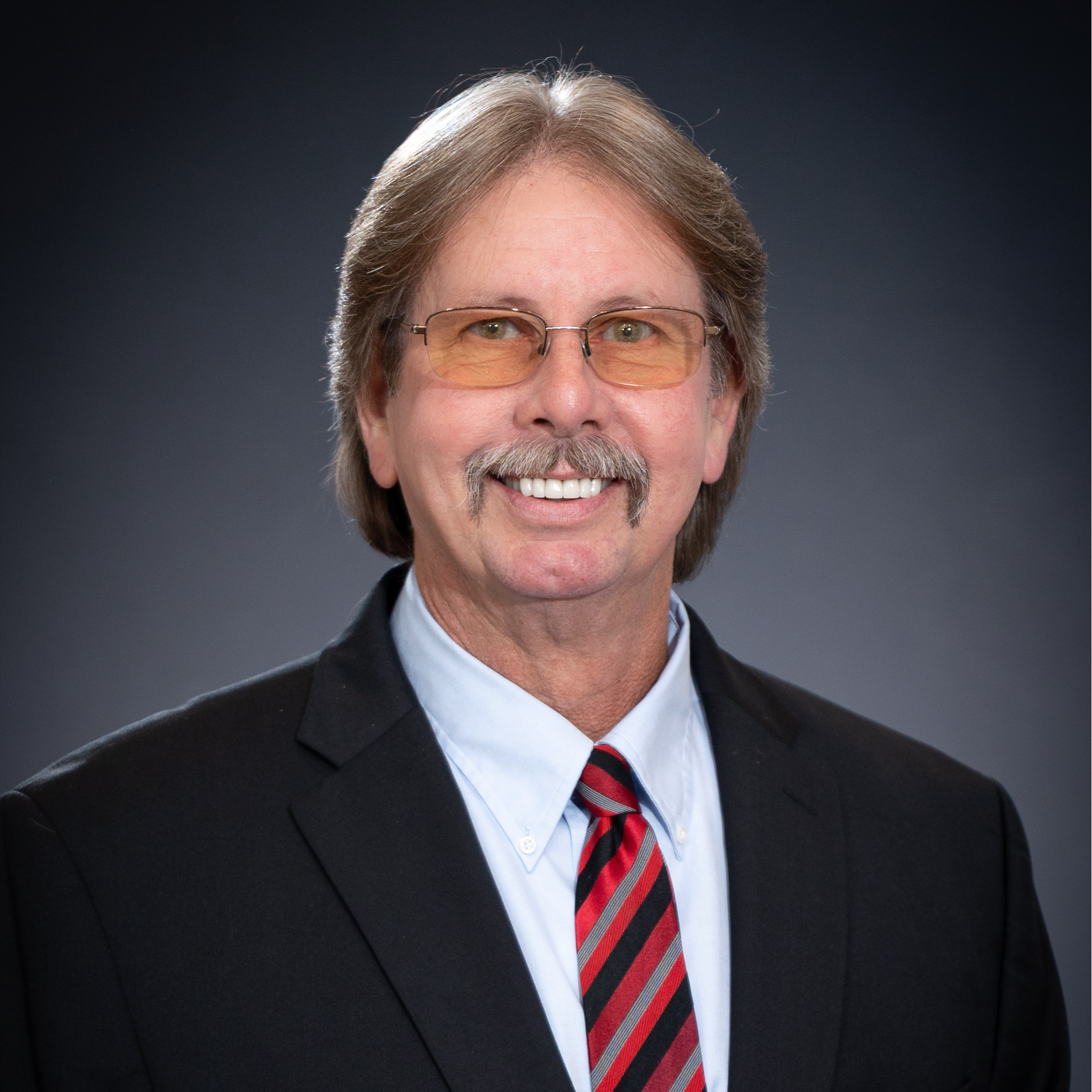 headshot of Alderman Larry Harmon with black suit and red and black striped tie