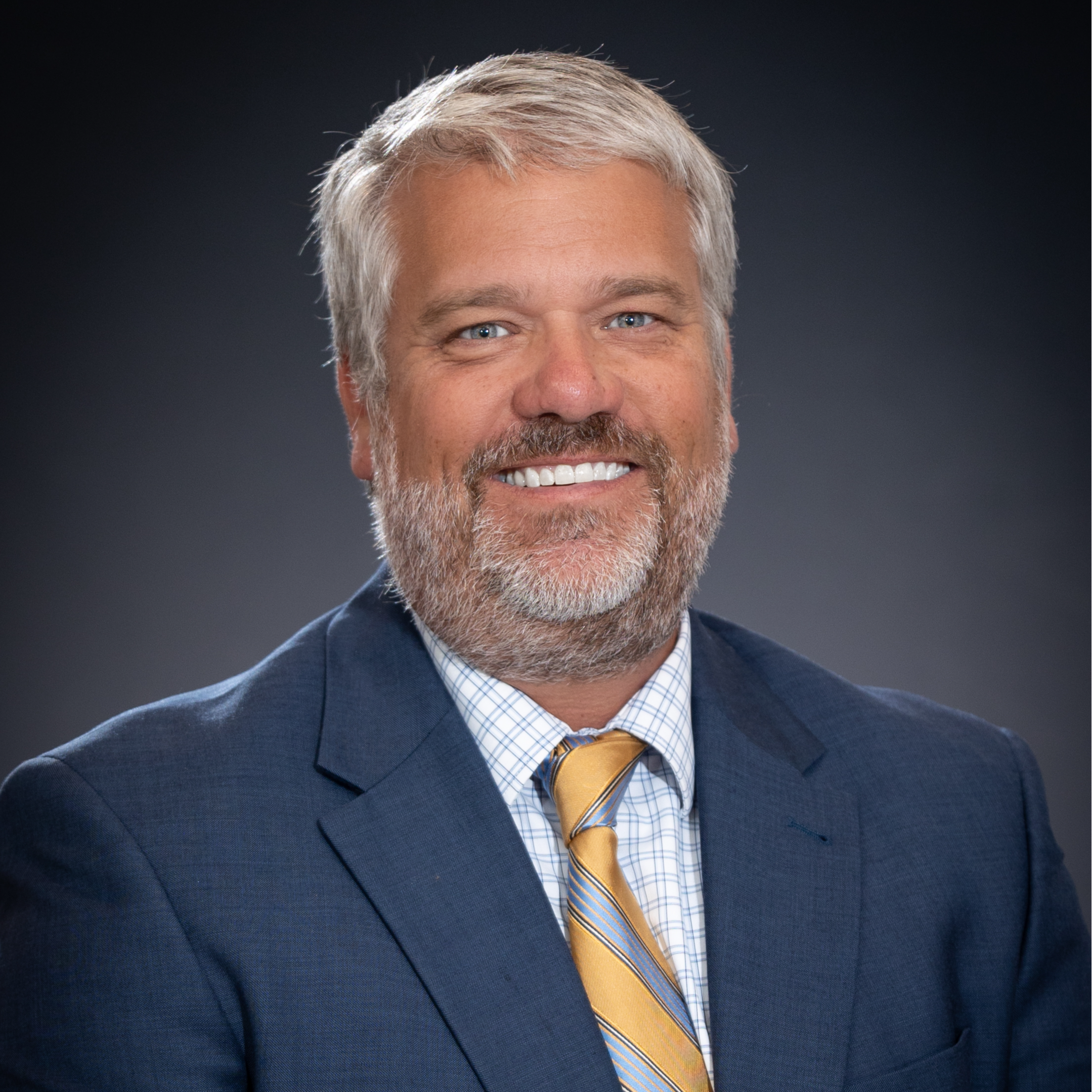 Headshot of Alderman Jeff McKee in gray suit with yellow and gray striped tie