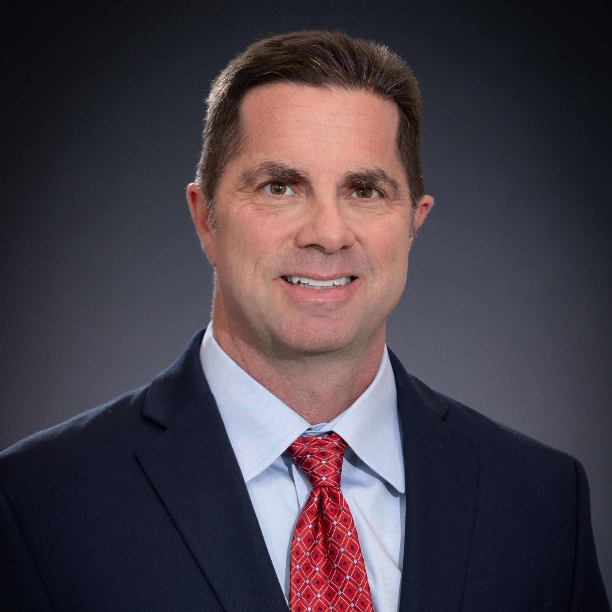 Headshot of Alderman Jeremy Biggs in black suit with red tie