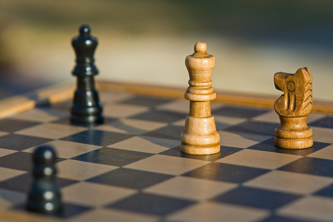 Picture of black and light wood chess pieces on a chess board