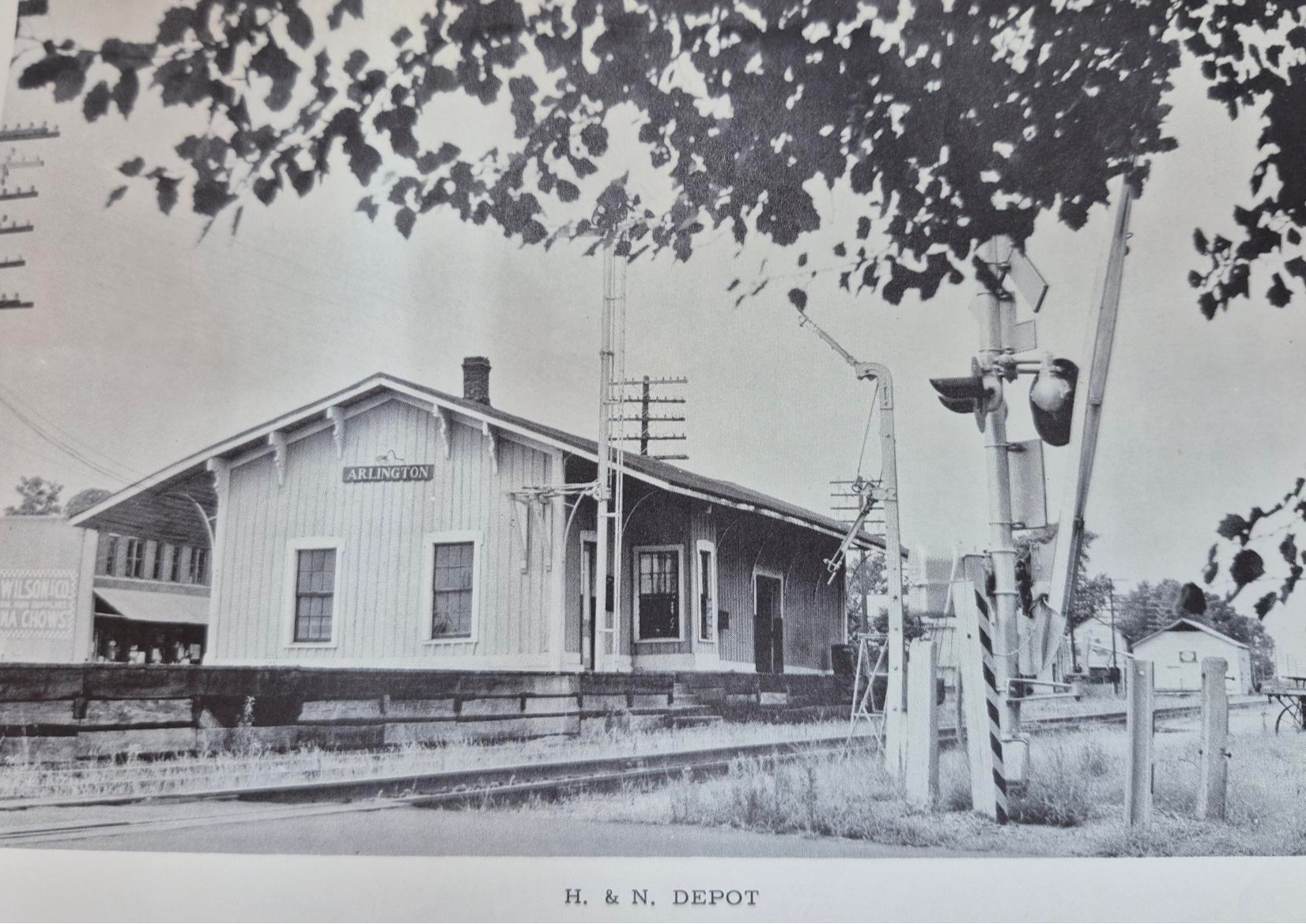 black and white picture of historic H&N Depot, with a sign on end of building that says "Arlington"