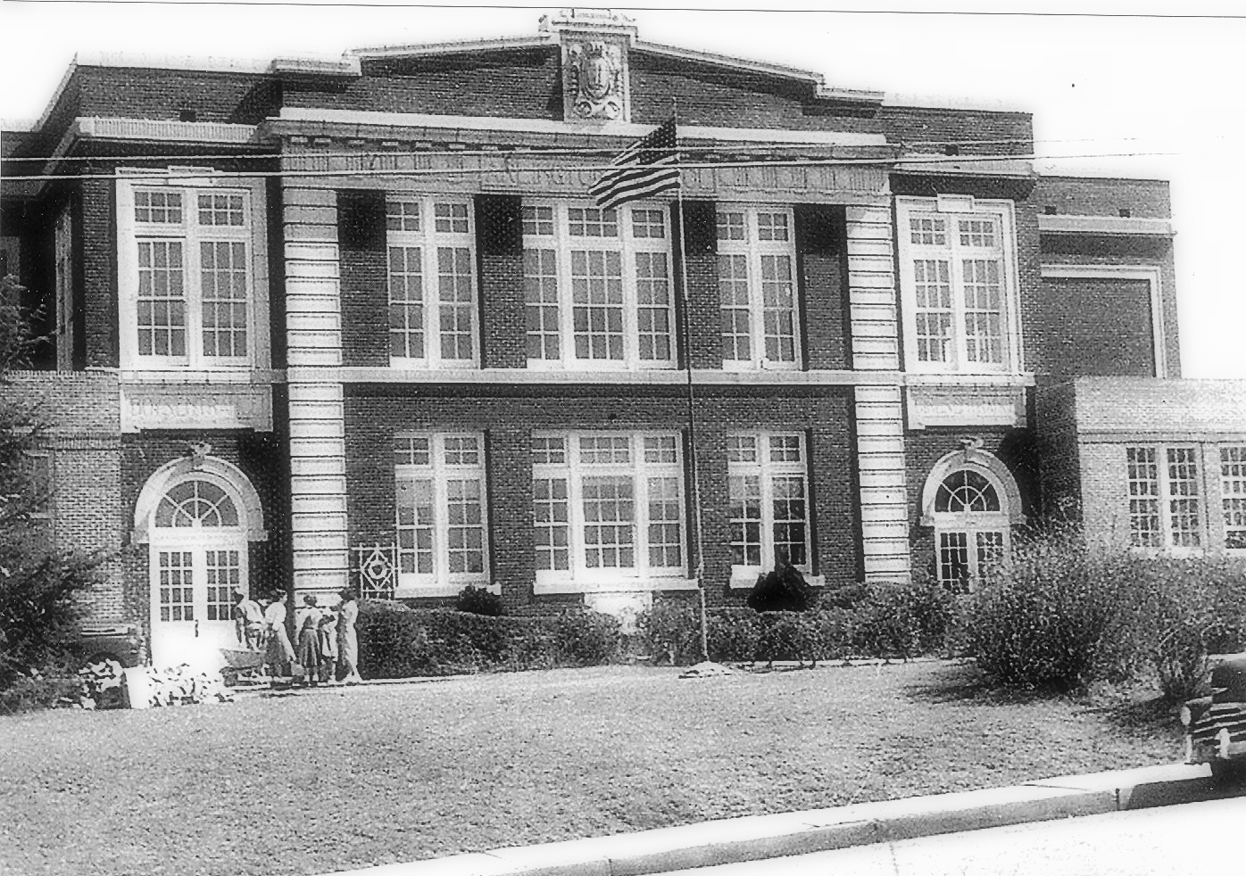 Black and white picture of two-story brick school  with white columns and windows