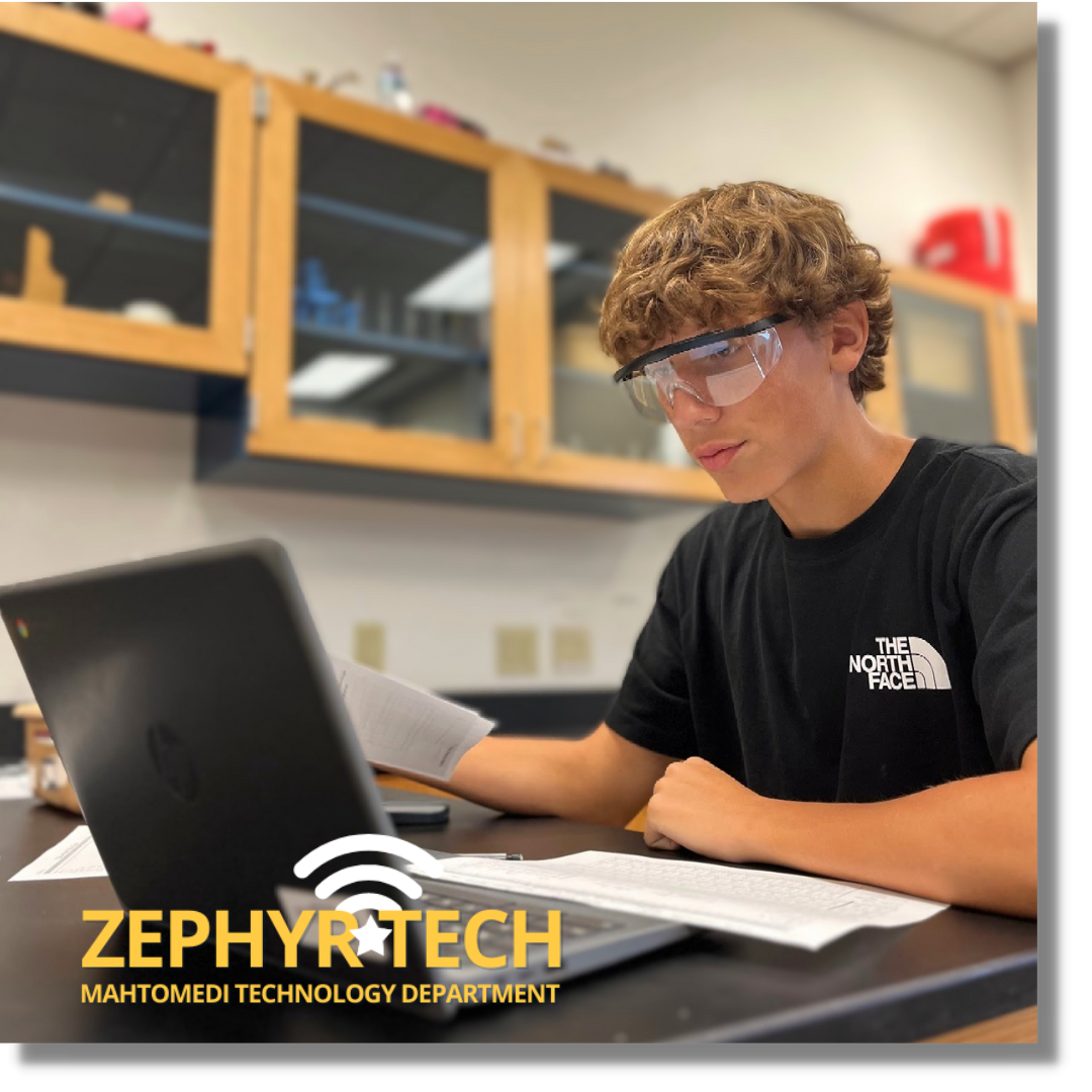 student with safety glasses in front of a laptop