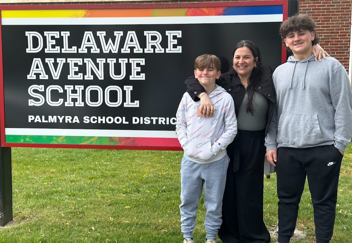 Principal Norton with her sons in front of the delaware avenue school sign