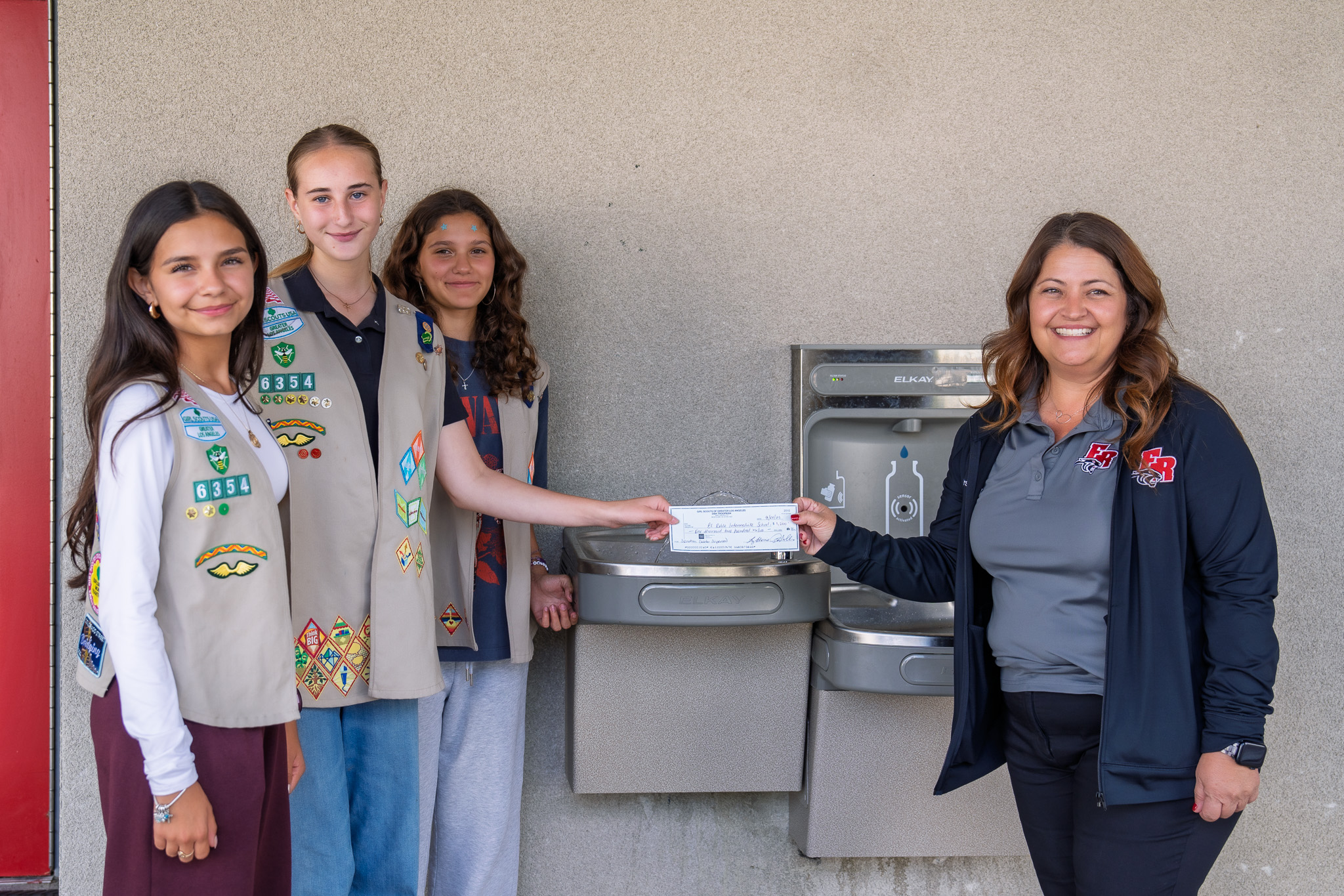 Students handing a check to their former principal for the work they did in MYP to install new water fountains at school.