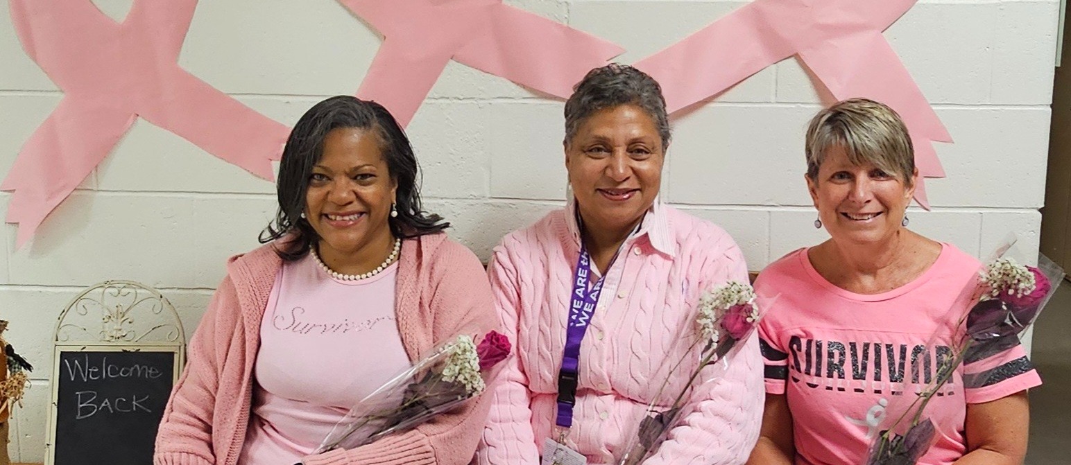 3 ladies sitting in front of pink ribbons