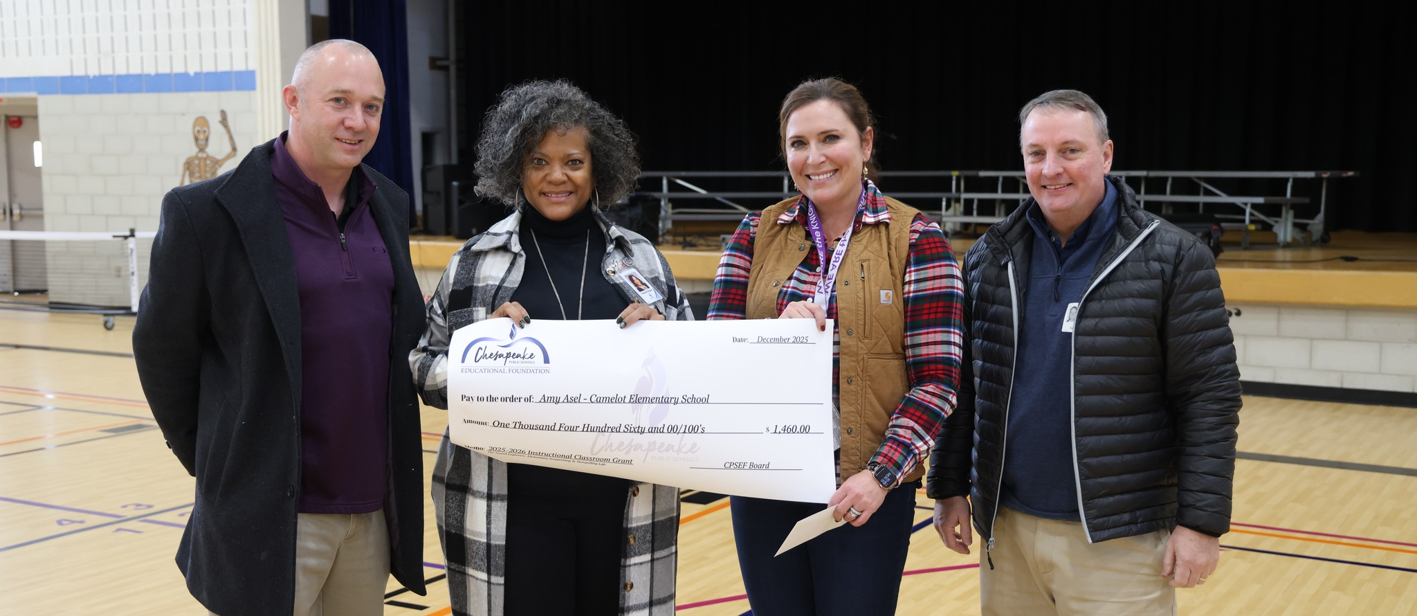 2 men and 2 ladies. the ladies are holding a giant grant check
