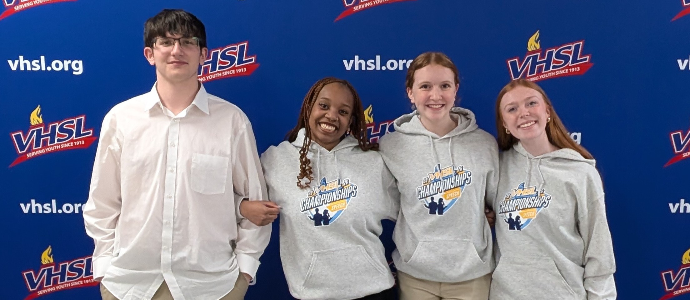 Speech and debate team standing with their awards