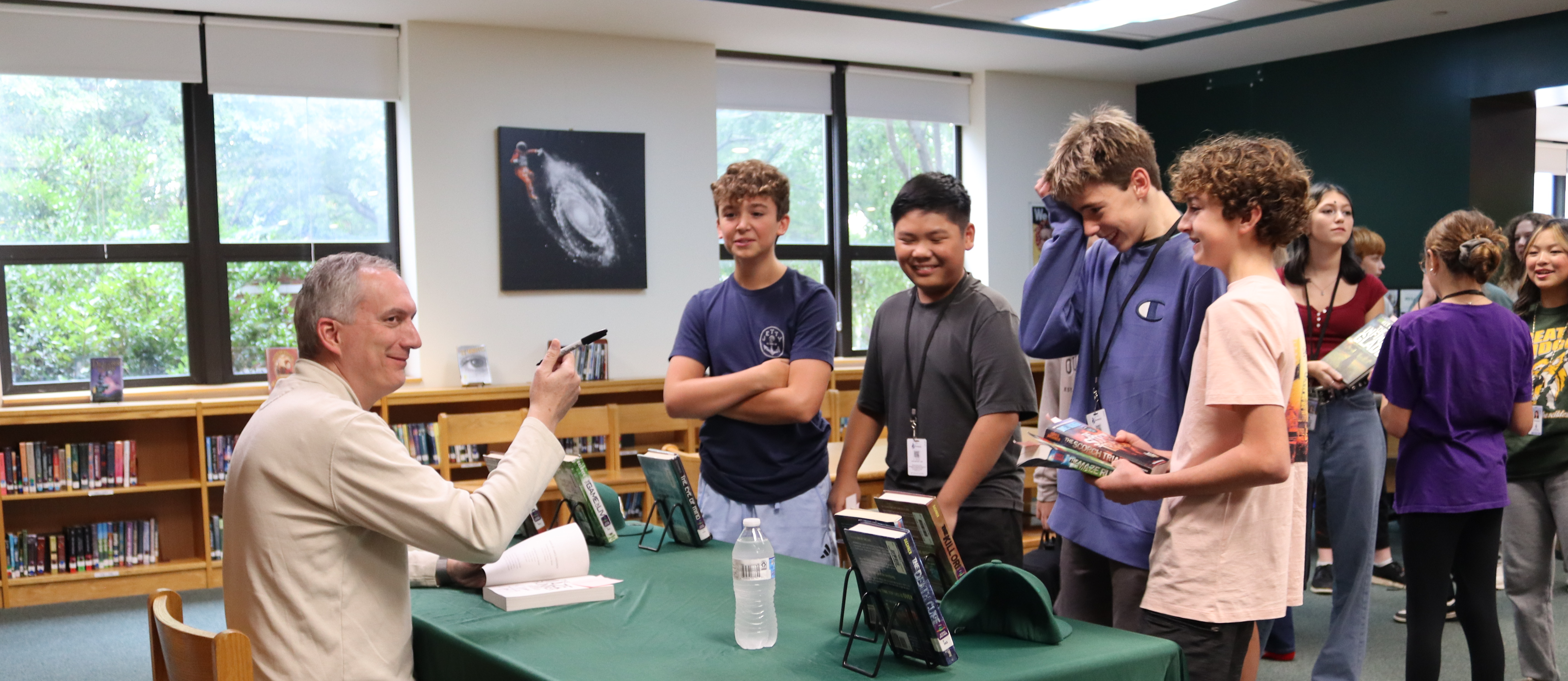 Photo of author James Dashner who is signing books for four GBMS students in the school's media center.