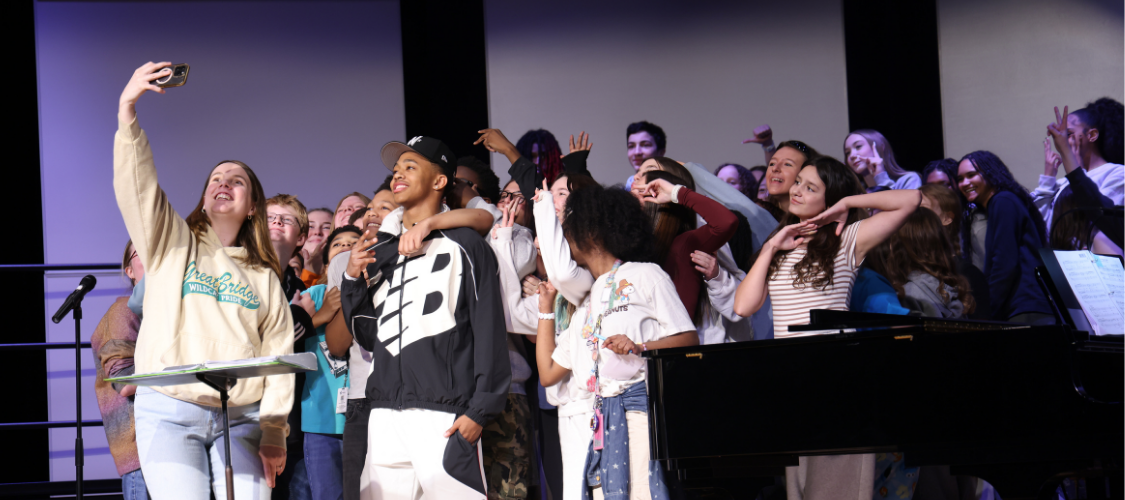 Chorus students taking a photo with Olympian Quincy Wilson