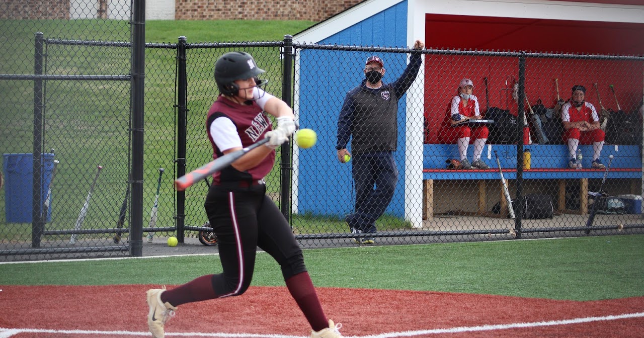 girl hitting the ball with the bat on the softball field