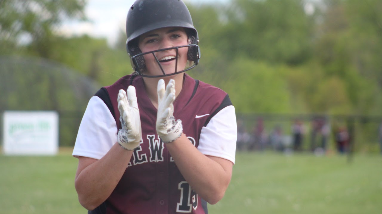 girl wearing the softball uniform and clapping her hands