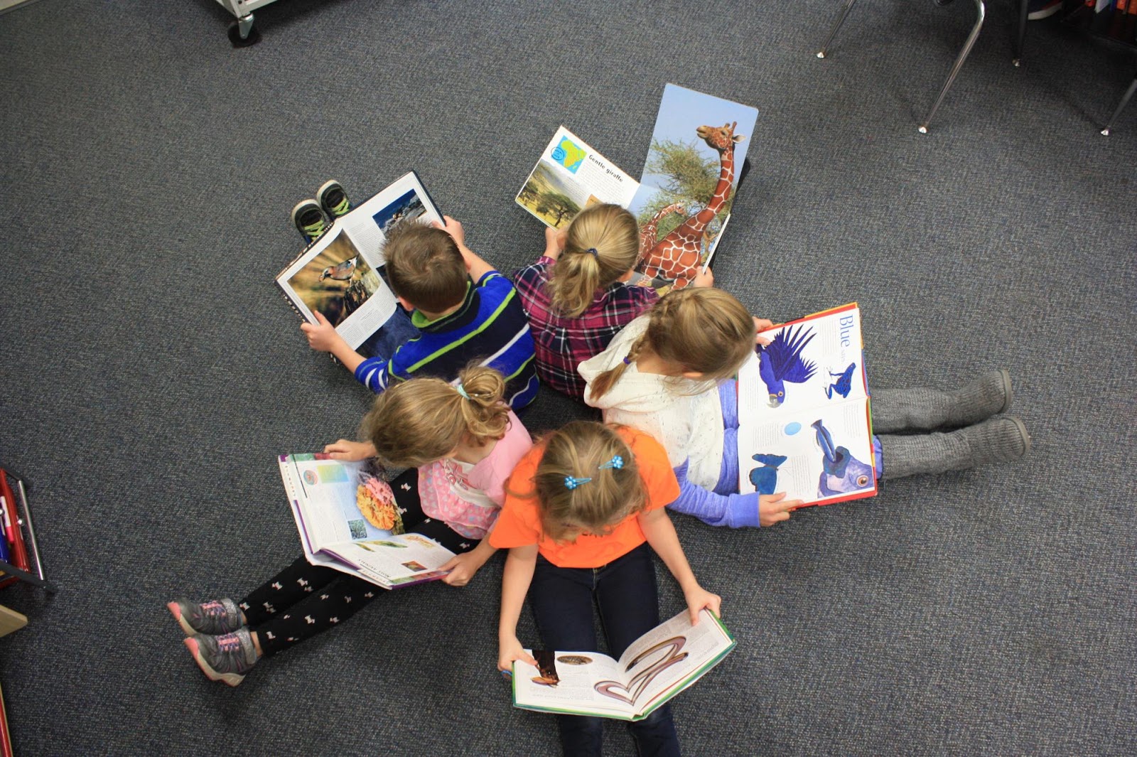 Students in a circle with their back against each other holding books