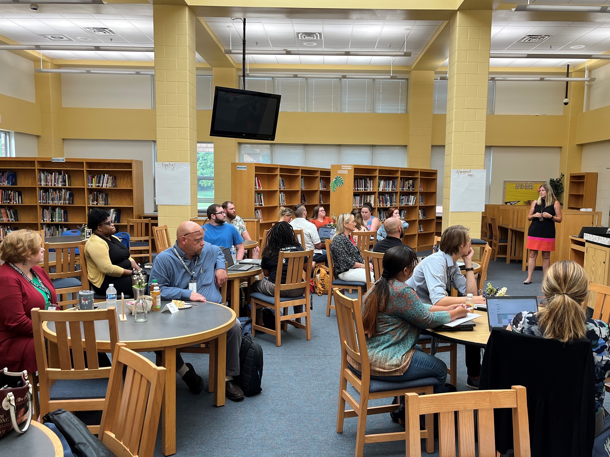 teachers sitting at table listening to a speaker