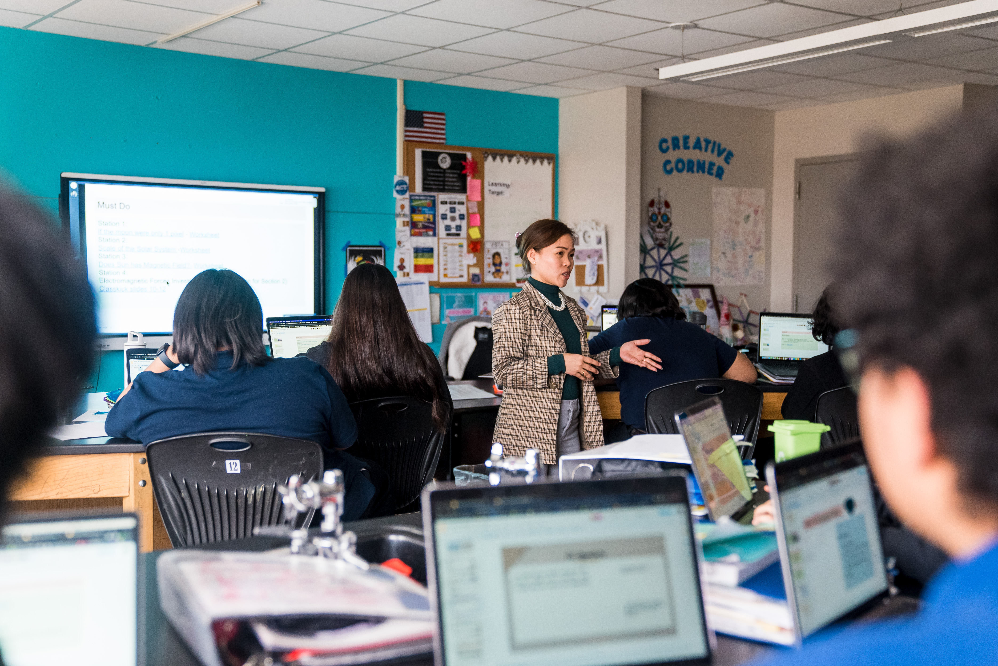 Teacher in blazer addressing her class on their laptop computers.